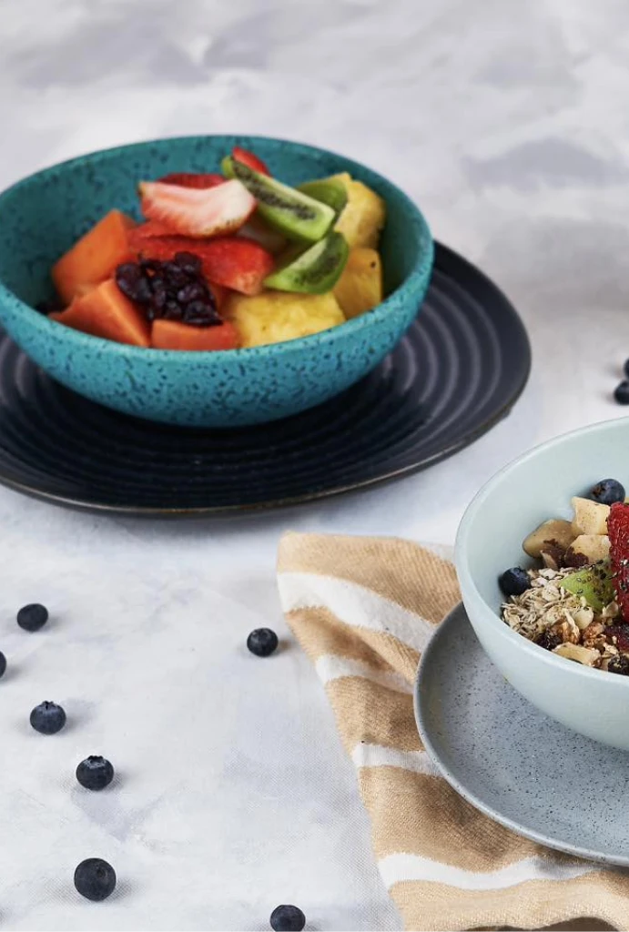 Cuencos con frutas variadas y ar&aacute;ndanos esparcidos sobre la mesa.