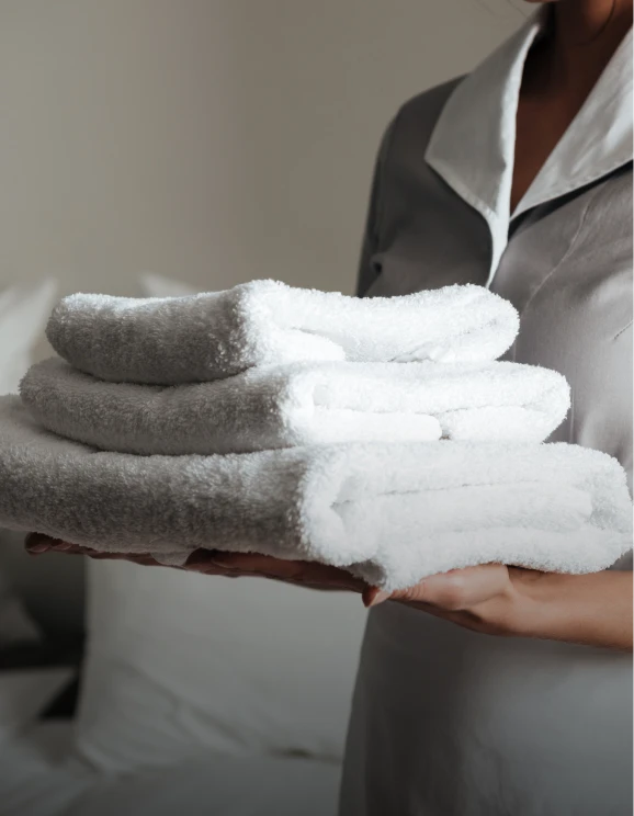Persona sosteniendo toallas blancas dobladas.