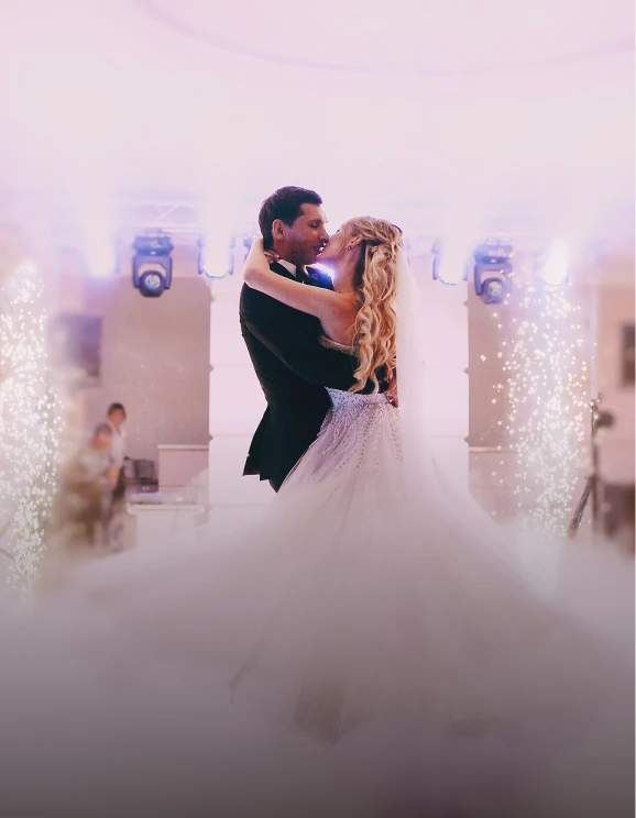 Pareja bailando en su boda rodeada de luces y humo.