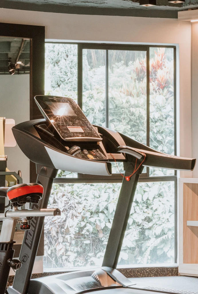 Caminadora moderna en un gimnasio con ventana al fondo iluminada.
