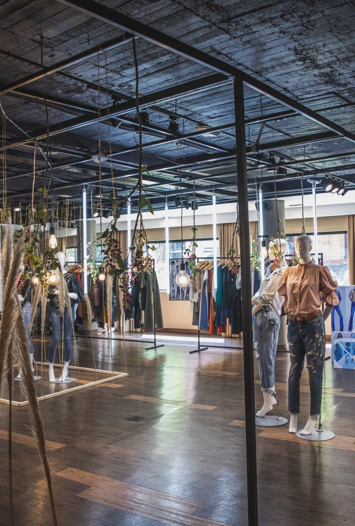 Tienda de ropa moderna con maniqu&iacute;es y decoraci&oacute;n colgante.