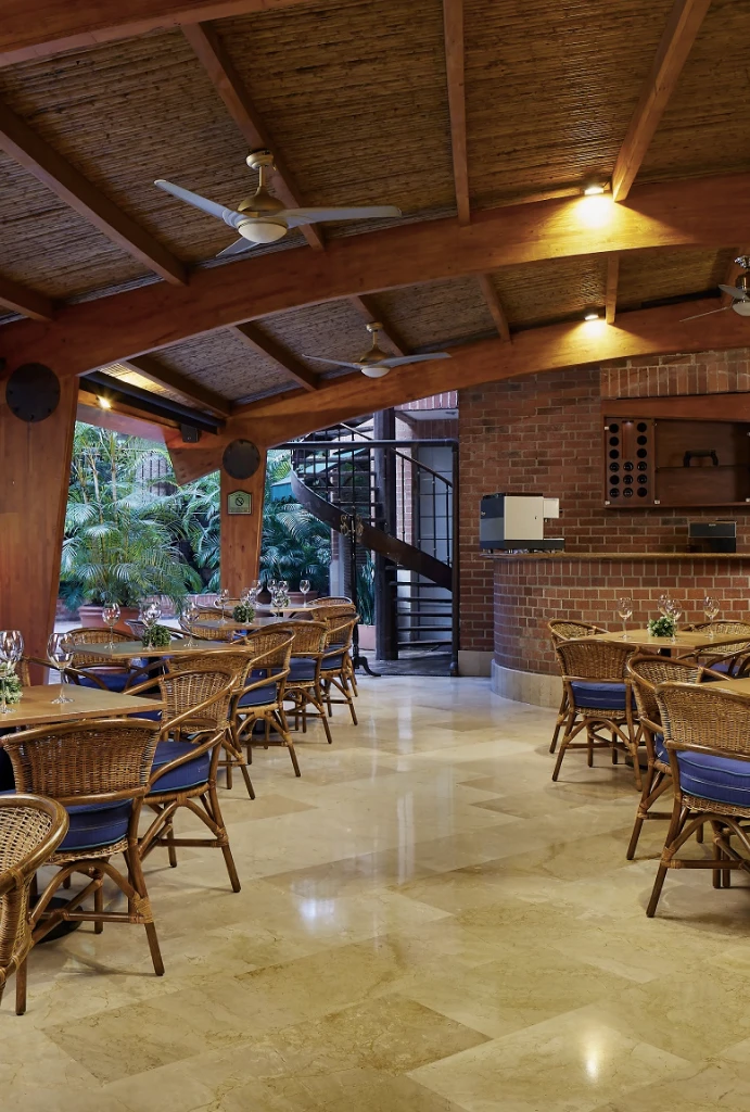 Restaurante con mesas y sillas de mimbre bajo techo de madera y palma.