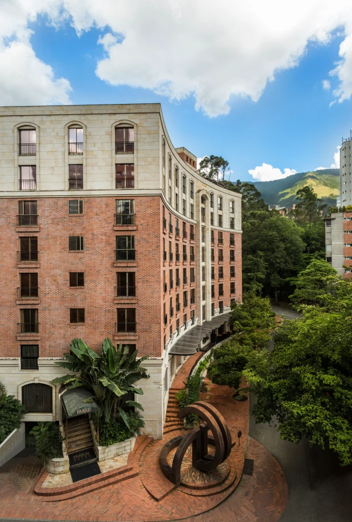 Edificio de ladrillo con escultura al frente, rodeado de &aacute;rboles.