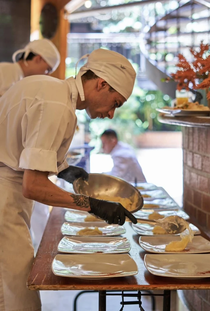 Chef en la cocina, sirviendo platos con una mezcla cremosa.