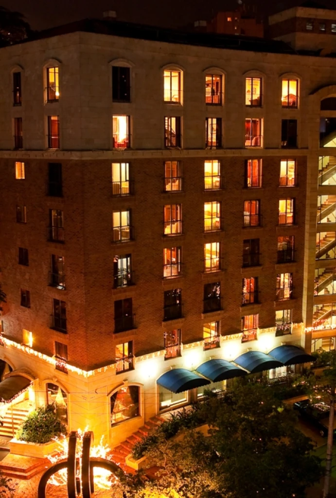 Edificio iluminado por la noche con ventanas brillantes y toldos azules.