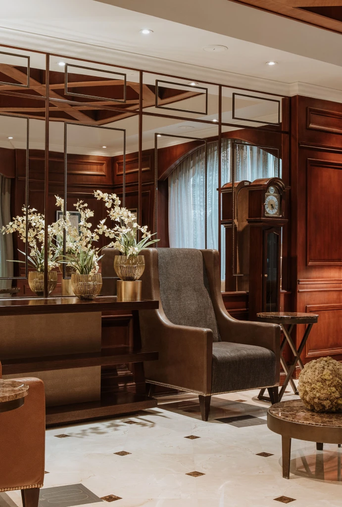 Sala elegante con sillas, espejo y decoraciones florales en tonos marrones.