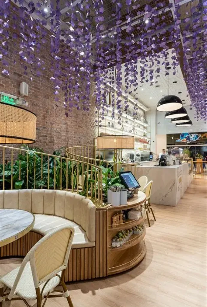 Caf&eacute; elegante con decoraciones violetas colgantes y asientos curvos y acogedores.