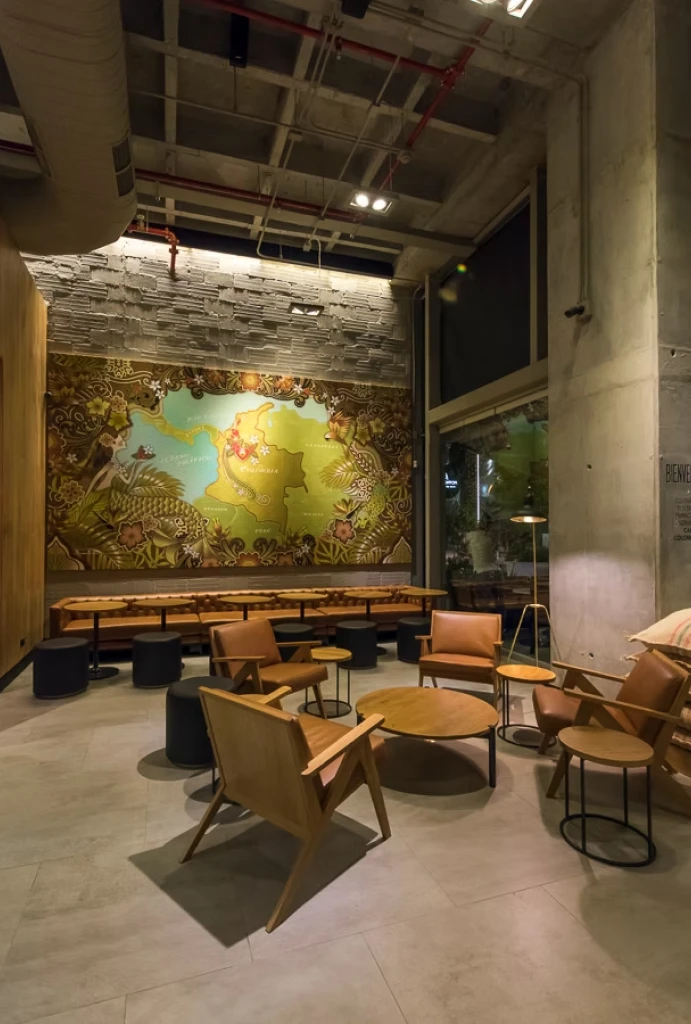 Cafeter&iacute;a moderna con mural colorido y sillas de madera en el interior.