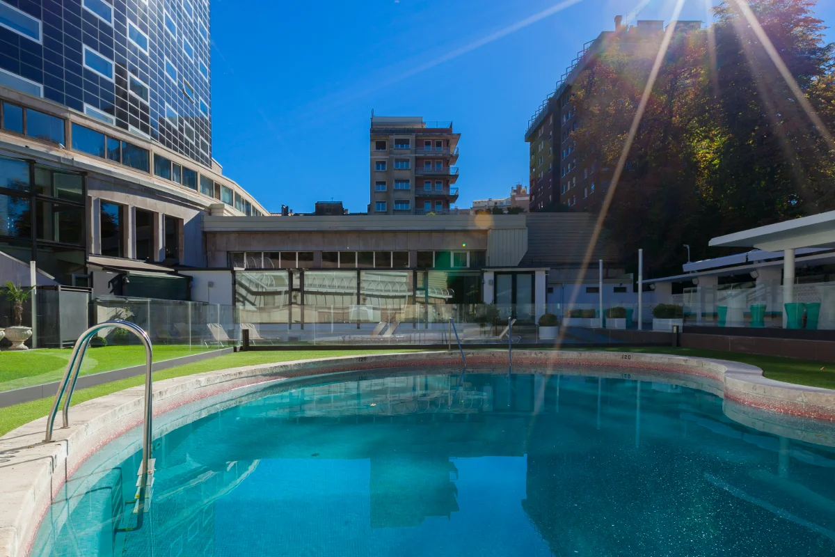 Piscina al aire libre rodeada de edificios y cielo despejado.