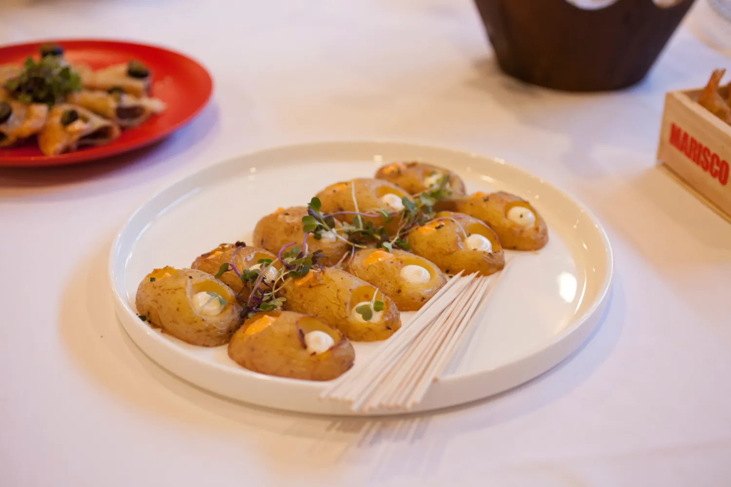 Plato de papas rellenas con decoraci&oacute;n verde sobre una mesa blanca.