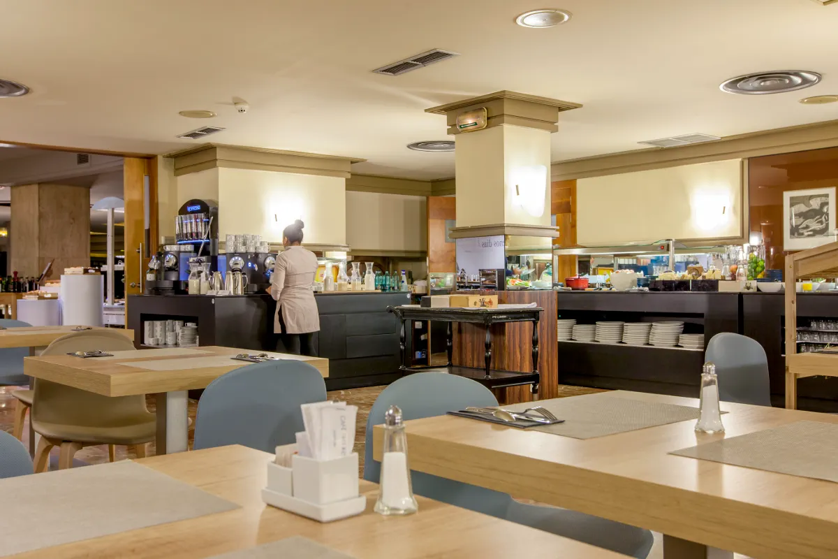 Cafeter&iacute;a moderna con alguien preparando caf&eacute; detr&aacute;s del mostrador.