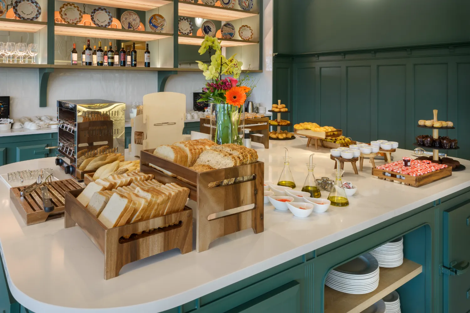 Buffet con panes, aceites y flores sobre encimera en cocina elegante.