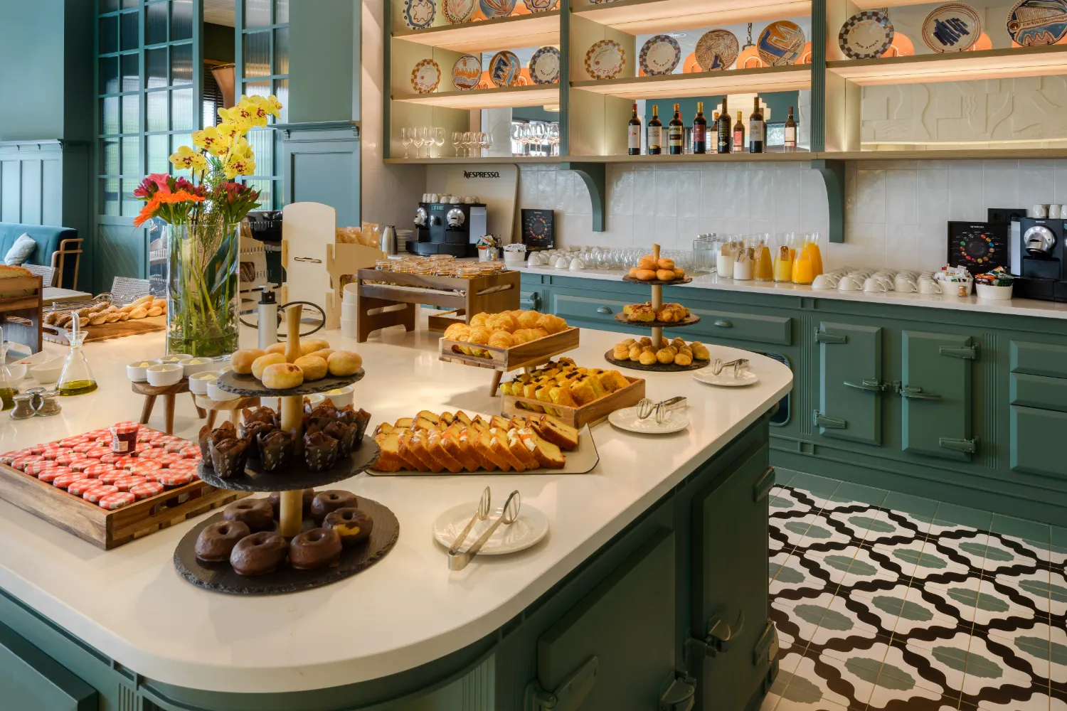 Mesa con variedad de pasteles, pan, y bebidas en un entorno de cafeter&iacute;a elegante.
