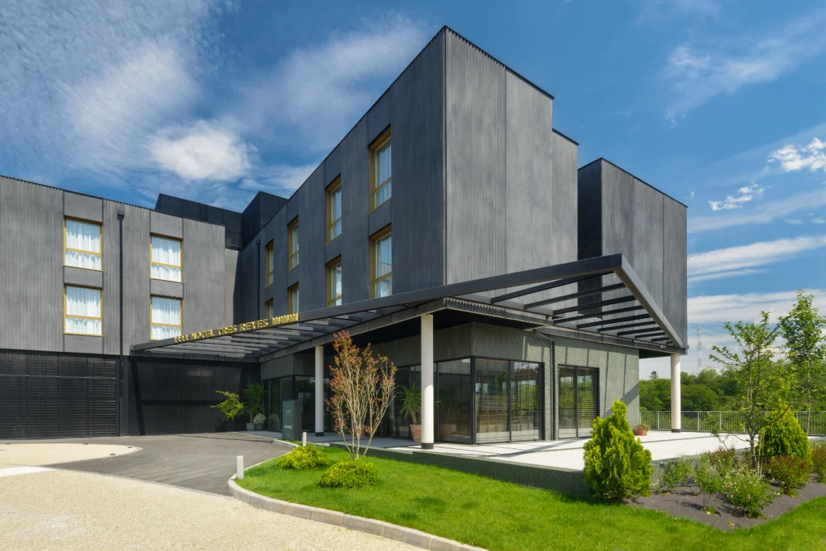 Edificio moderno bajo un cielo azul con vegetaci&oacute;n alrededor.