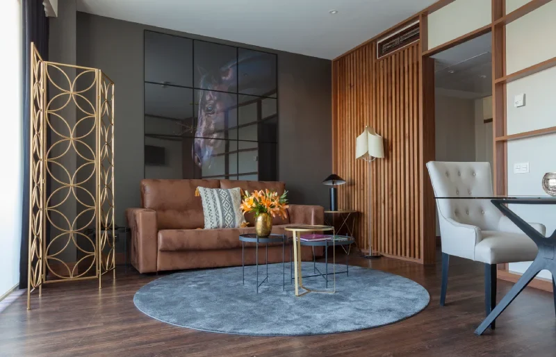 Sala moderna con sof&aacute; marr&oacute;n, alfombra gris y decoraci&oacute;n elegante.