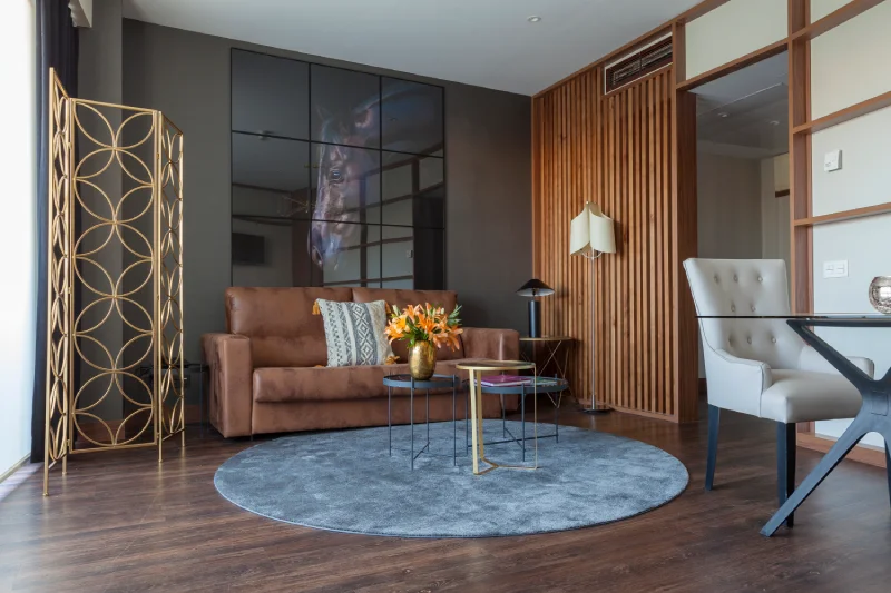 Sala moderna con sofá marrón, alfombra gris y decoración elegante.
