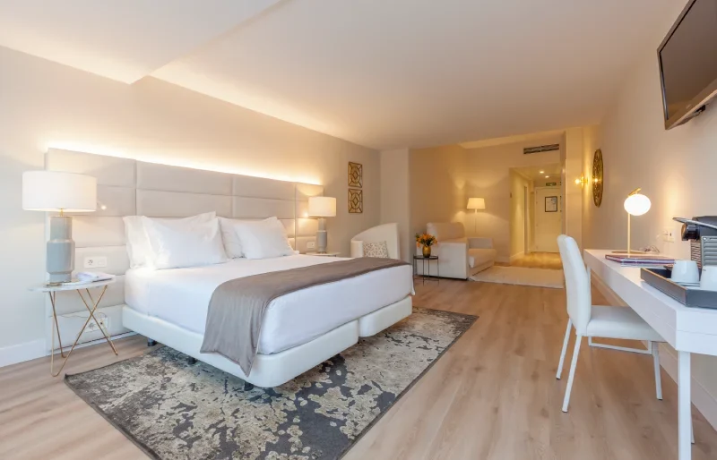 Habitaci&oacute;n moderna de hotel con cama grande, escritorio y l&aacute;mparas.
