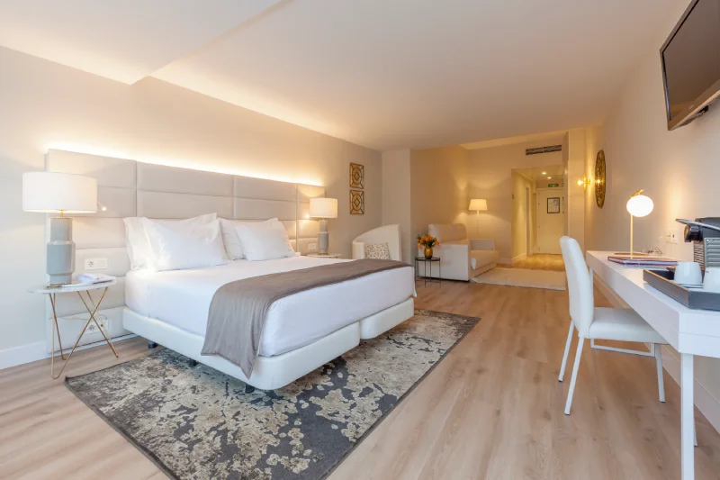 Habitación moderna de hotel con cama grande, escritorio y lámparas.