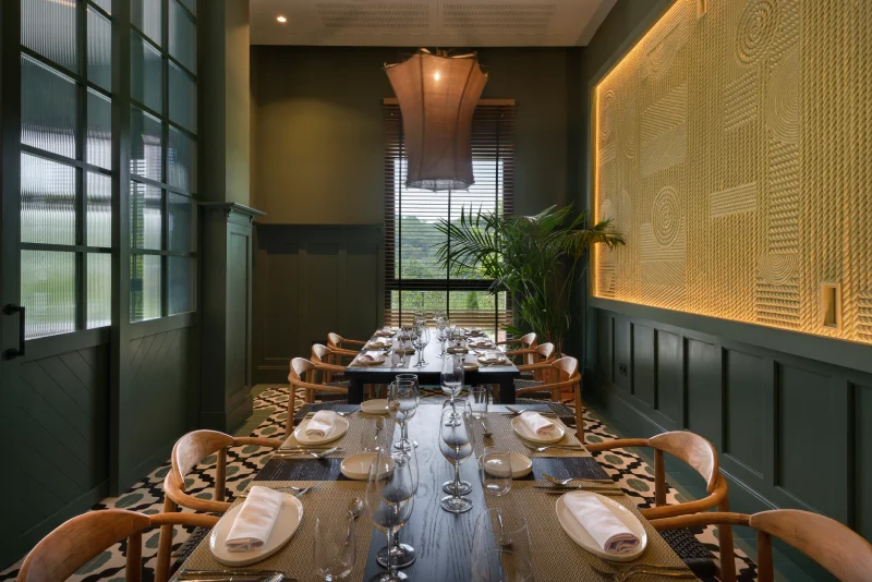 Comedor elegante con mesa servida, decoración verde y luz suave.
