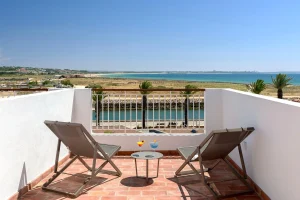 Duas espregui&ccedil;adeiras e coquet&eacute;is em terra&ccedil;o com vista para o mar.