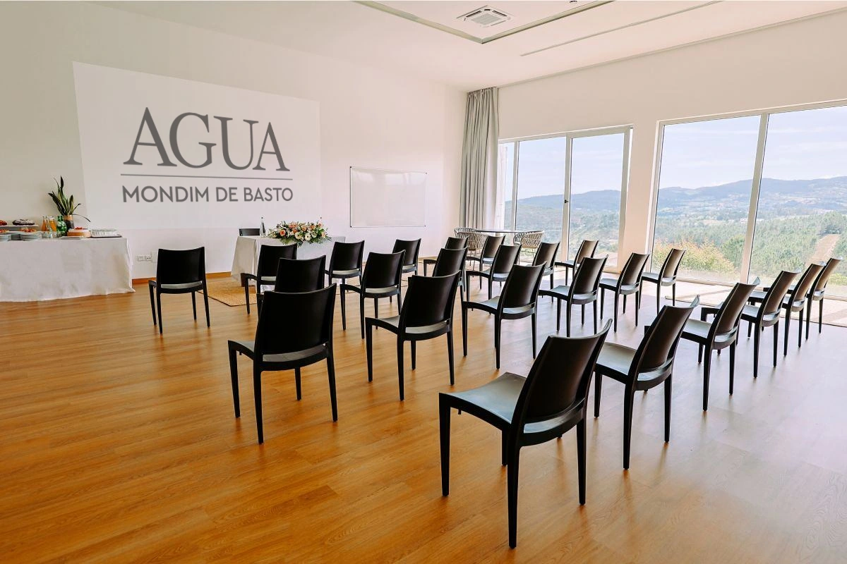 Sala de reuni&otilde;es com cadeiras e mesa, vista panor&acirc;mica ao fundo.