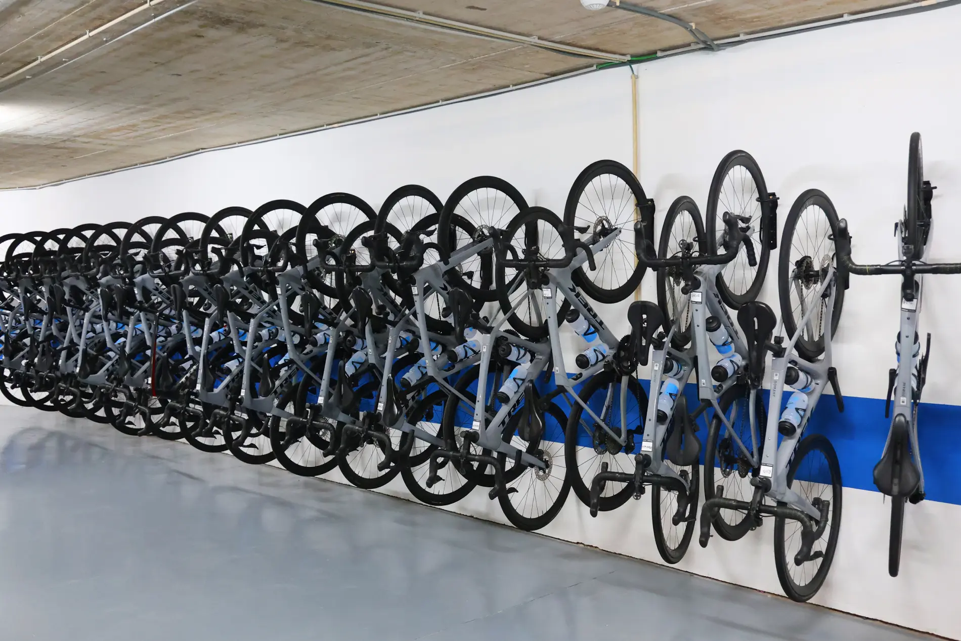 Bicicletas penduradas em suporte de parede em estacionamento coberto.