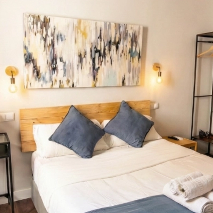 Cama con almohadones azules y arte abstracto sobre el cabecero.