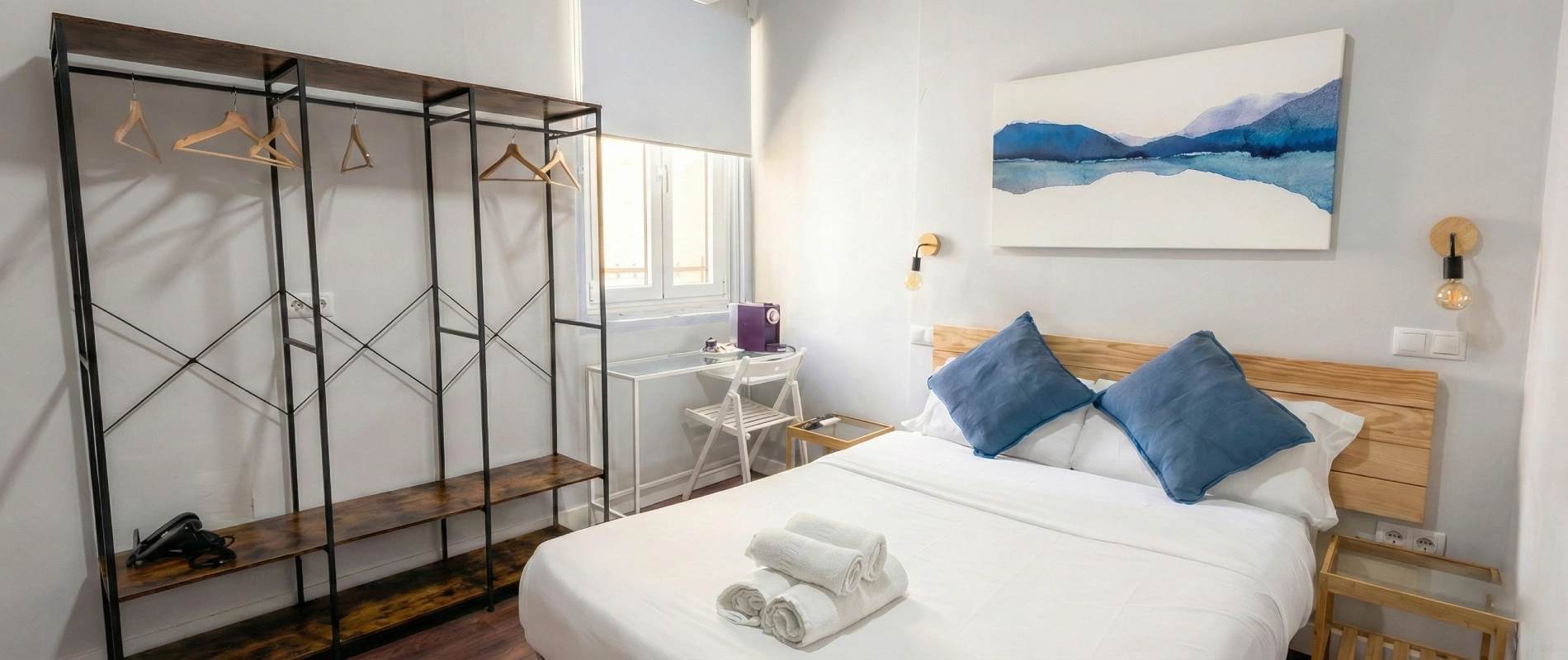 Habitaci&oacute;n con cama, decoraci&oacute;n azul y estante vac&iacute;o en la pared.