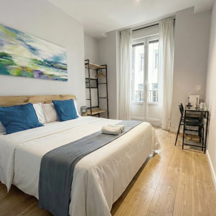 Habitaci&oacute;n acogedora con cama, ventana grande y decoraci&oacute;n moderna.