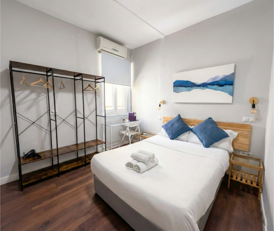 Habitaci&oacute;n moderna con cama doble, escritorio y percheros.