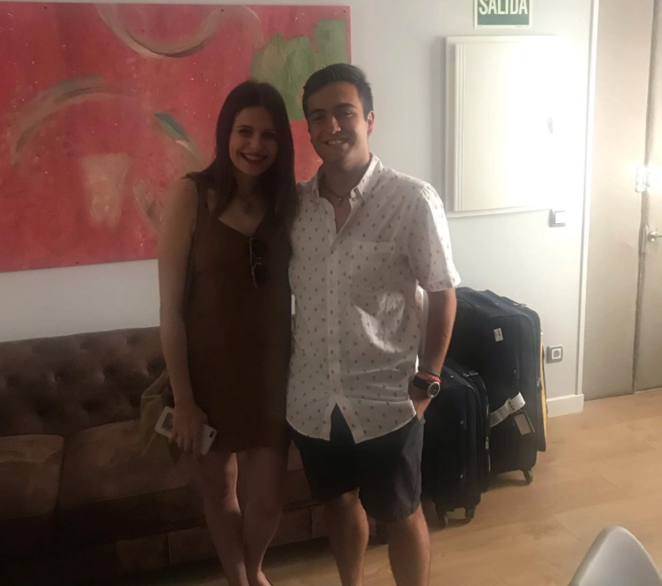 Dos personas posan frente a un sof&aacute; con maletas en el suelo.