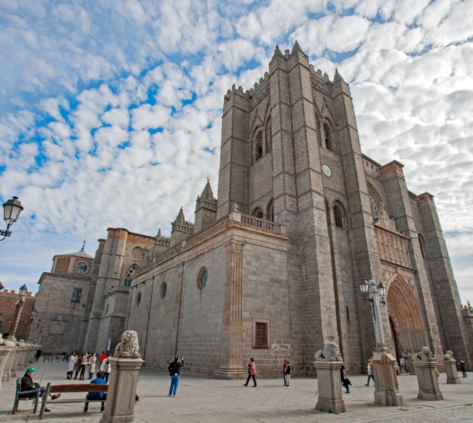 Catedral de piedra bajo un cielo nublado, con turistas caminando enfrente.