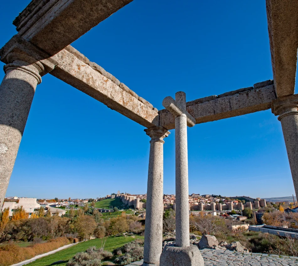 Vista de una estructura de piedra antigua con un paisaje urbano al fondo.