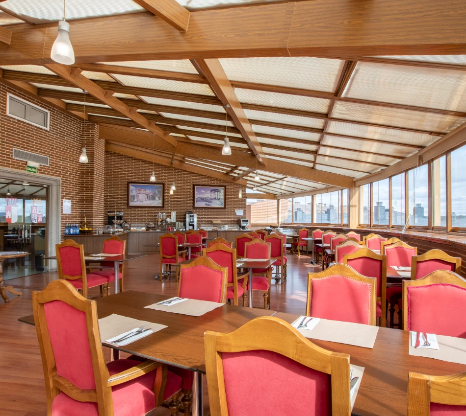 Restaurante amplio con sillas rojas y grandes ventanales.