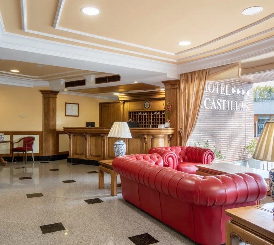 Recepci&oacute;n de hotel con sof&aacute; rojo y mostrador de madera.