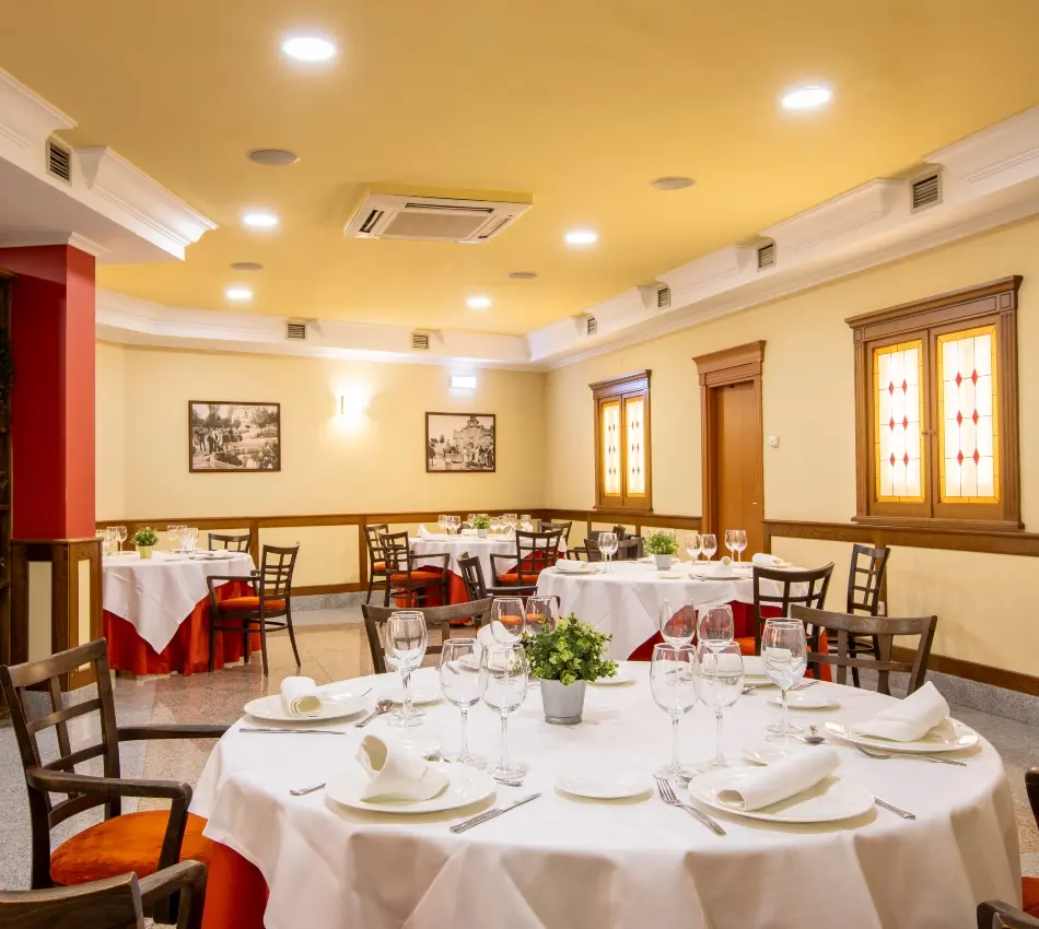Restaurante elegante con mesas redondas y manteles blancos, decoraci&oacute;n cl&aacute;sica.