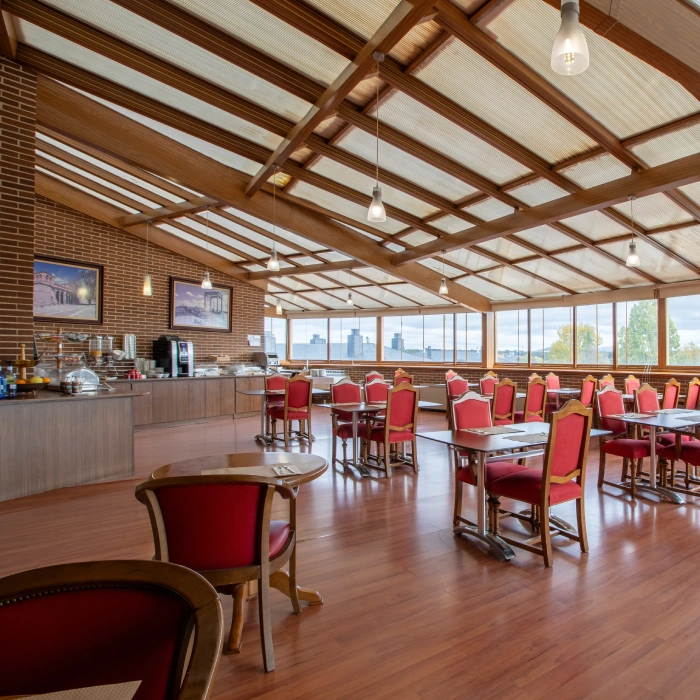 Comedor amplio con sillas rojas y techo de vidrio.