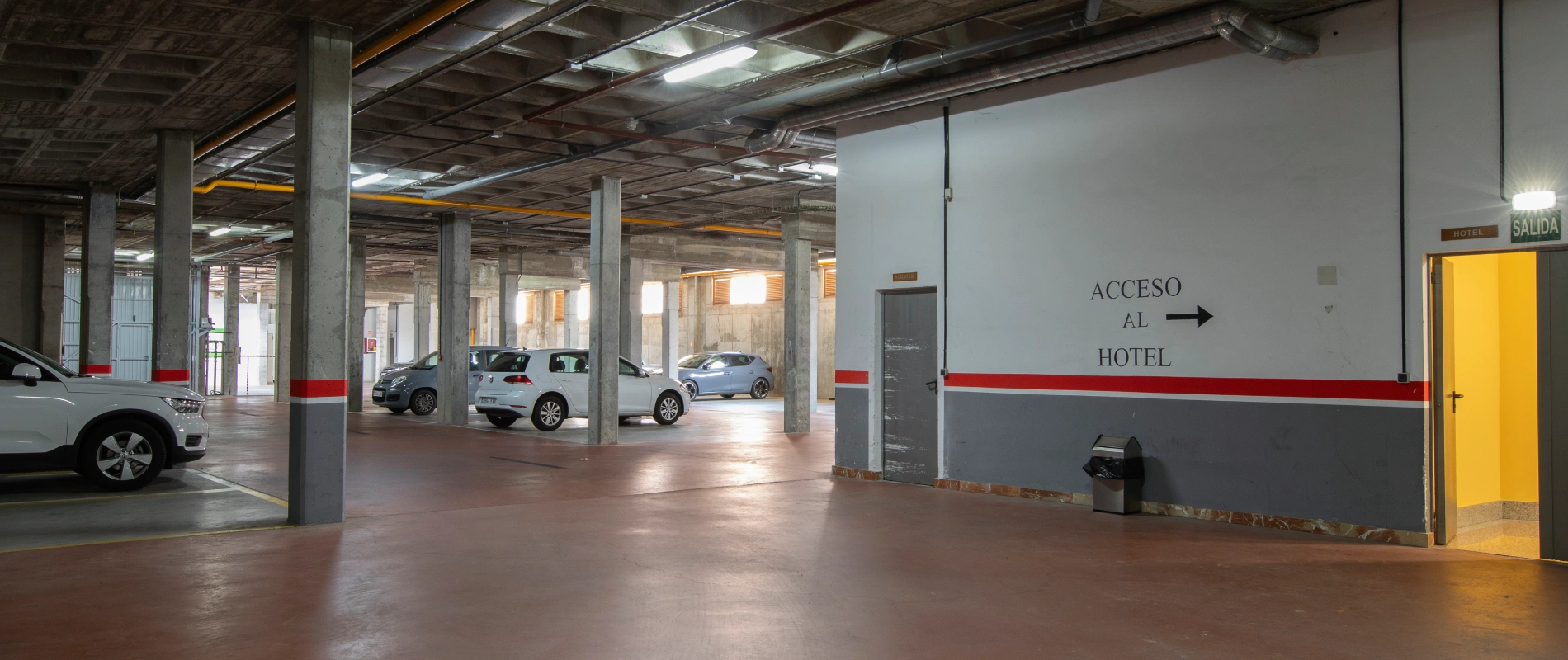 Estacionamiento con acceso al hotel indicado por flechas en la pared.