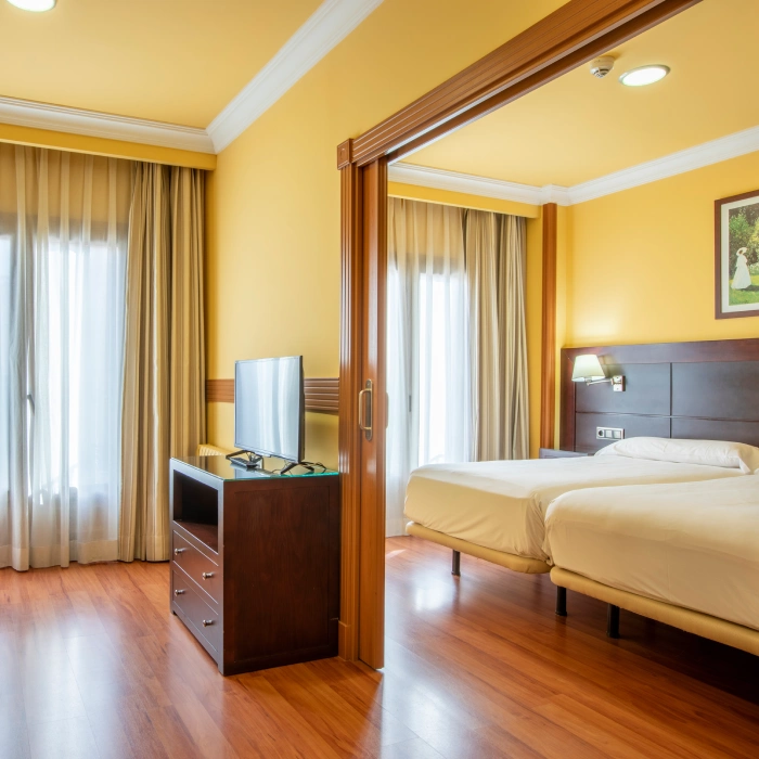 Habitaci&oacute;n de hotel con camas dobles y suelo de madera.