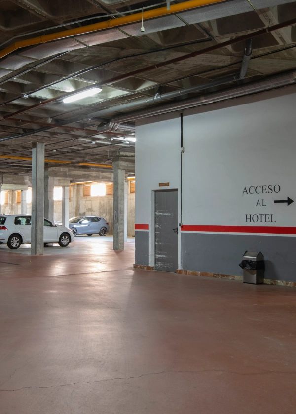 Estacionamiento subterr&aacute;neo con se&ntilde;al hacia el hotel en la pared.