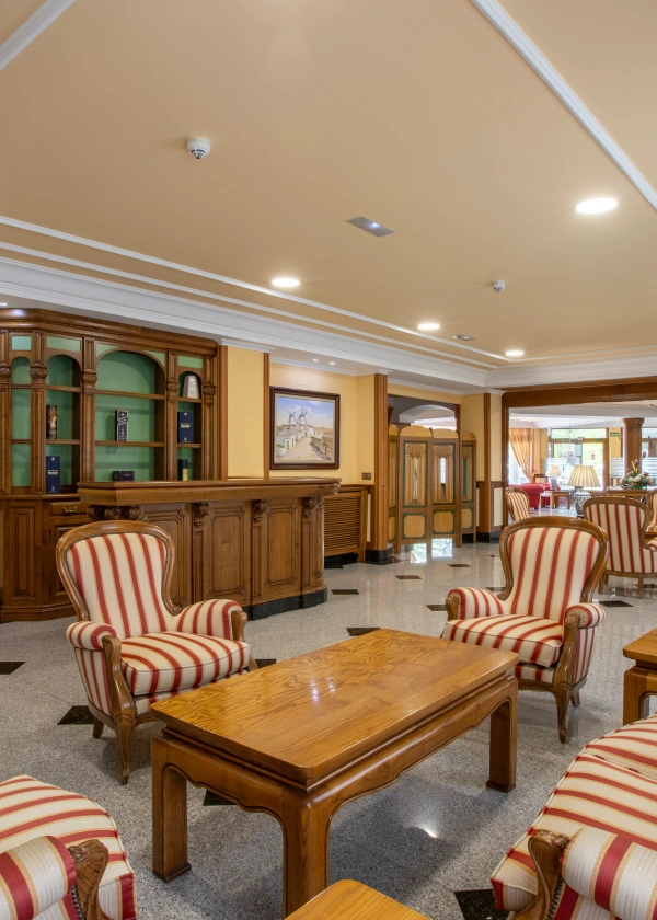 Sala elegante con sillones a rayas, mesa de madera y mueble de fondo.
