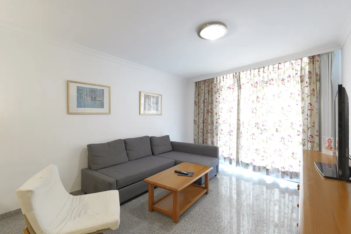 Sala de estar con sofá gris, silla blanca y mesa de centro de madera.