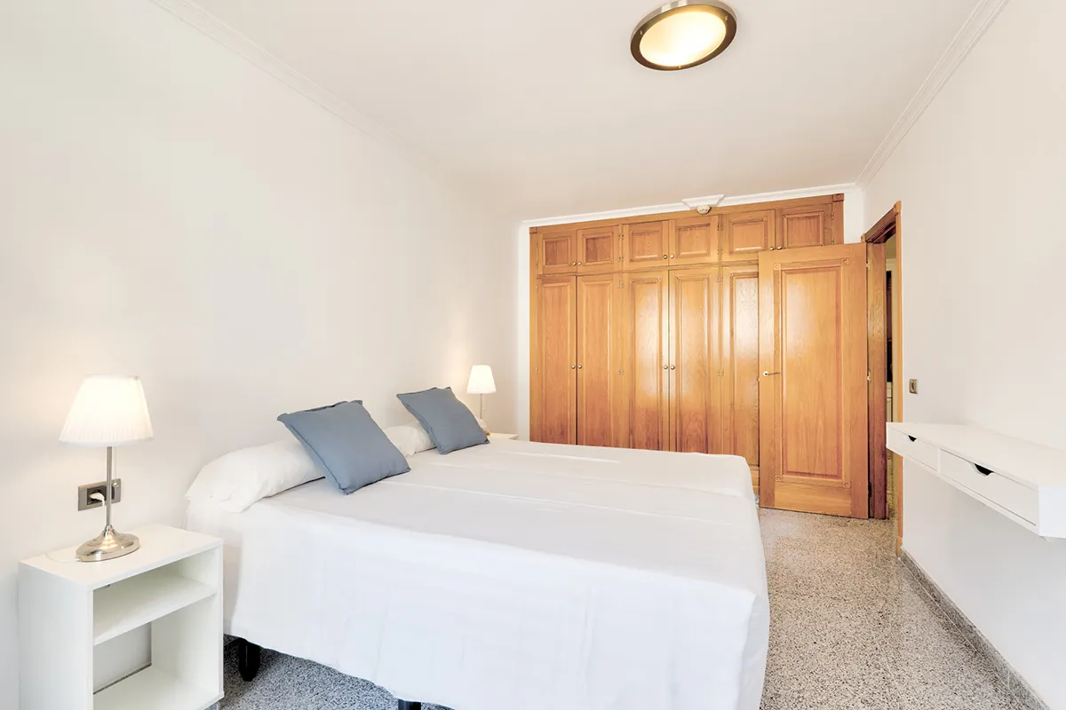 Habitación con dos camas, lámparas y armario de madera.