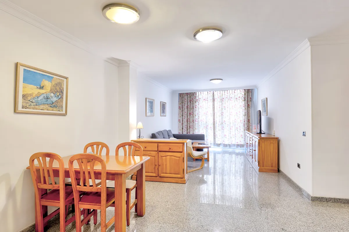 Sala de estar y comedor con muebles de madera y cortinas florales.