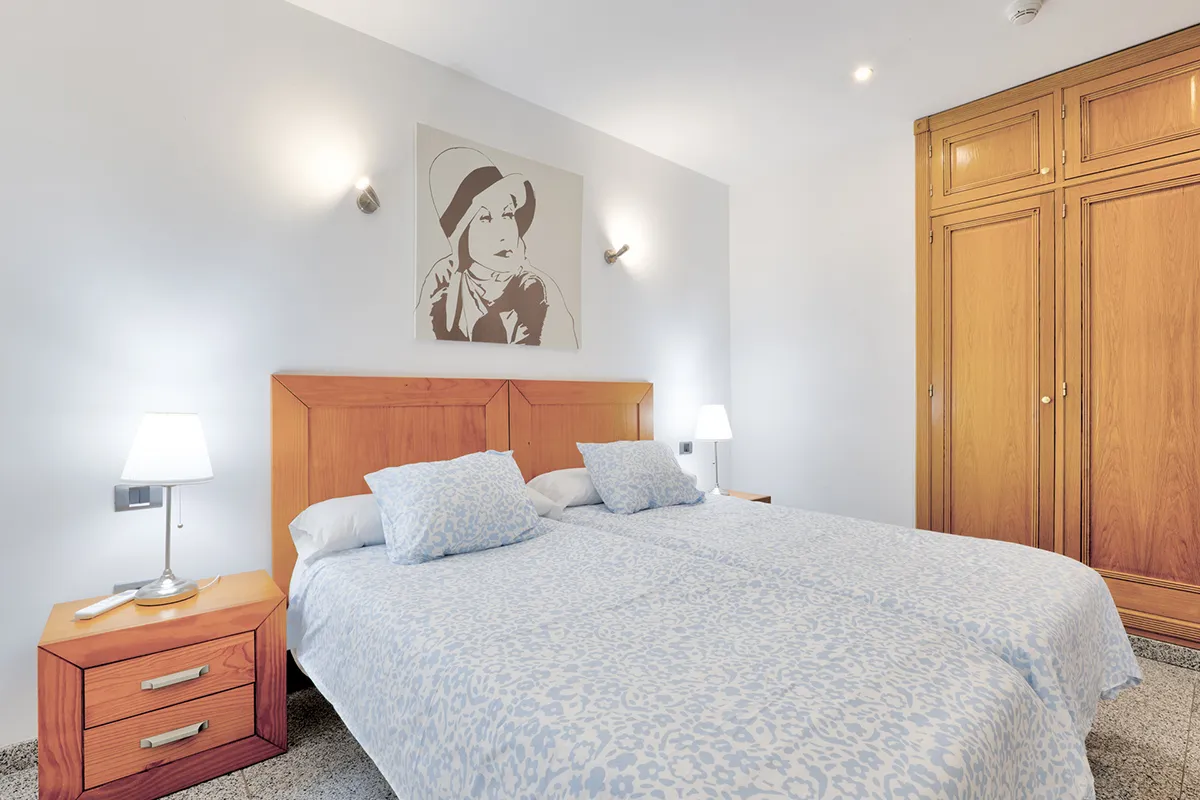 Dormitorio con dos camas, lámparas y un cuadro sobre la pared blanca.