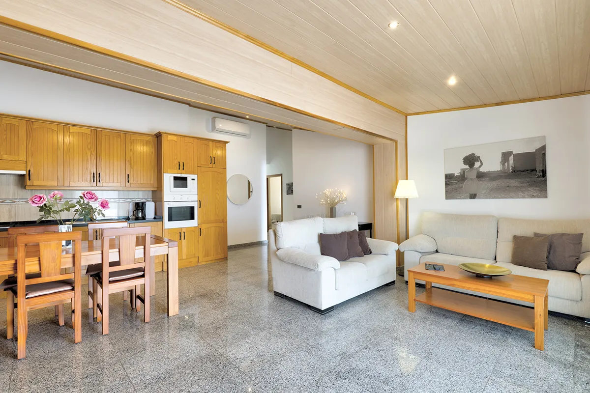 Sala de estar moderna con muebles de madera y cocina integrada.