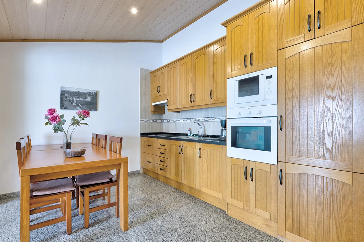 Cocina con muebles de madera y mesa con flores emulando un entorno acogedor.