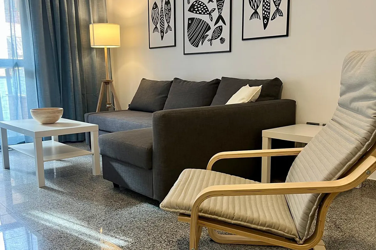 Sala moderna con sofá gris, sillón, mesa y decoraciones de peces negro.