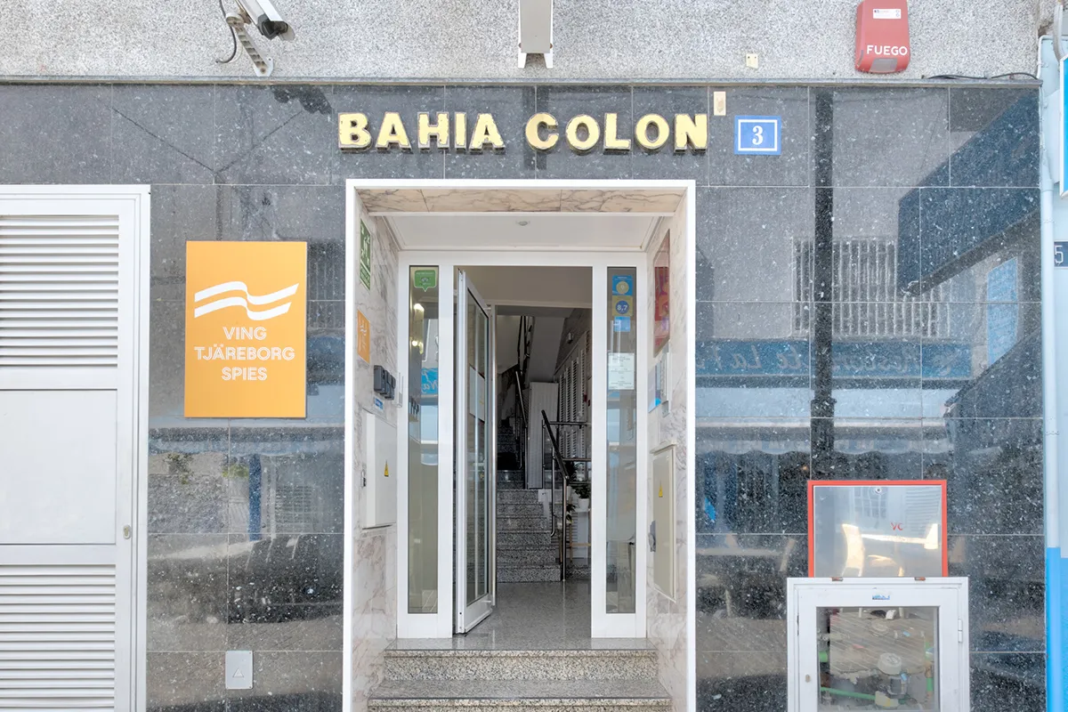 Entrada del edificio "Bahia Colon", con puerta de cristal y escalera interior.