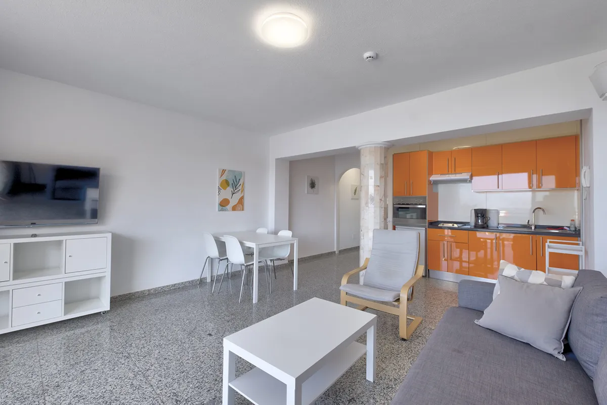 Sala moderna con cocina naranja y muebles minimalistas.